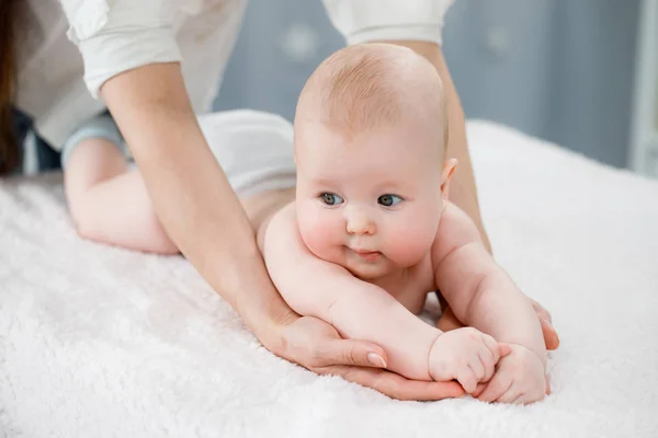 Maman fait de la gymnastique avec son bébé. Fond clair — Photo