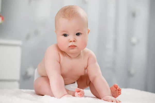 Bebê nu em uma fralda senta-se em um quarto brilhante — Fotografia de Stock