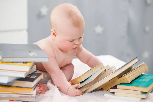 Mały chłopiec patrzy na stos książek. — Zdjęcie stockowe