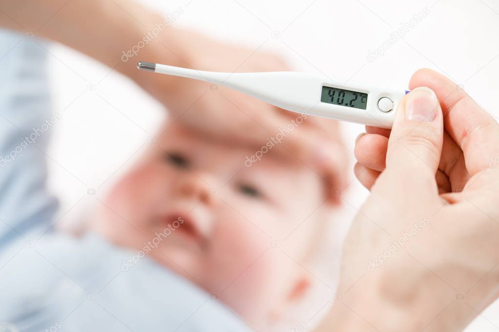 Close-up thermometer. Mother measuring temperature of her ill ki