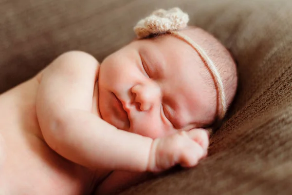 Bebé recién nacido con flor en la cabeza sobre fondo marrón —  Fotos de Stock