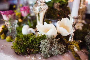 Rustik dekorasyon (orman yosunu, çiçekler, mumlar, gözlük ve vazolar). Akşam romantik atmosferi.