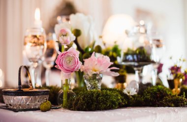 Rustik dekorasyon (orman yosunu, çiçekler, mumlar, gözlük ve vazolar). Akşam romantik atmosferi.