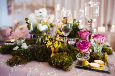 Rustik dekorasyon (orman yosunu, çiçekler, mumlar, gözlük ve vazolar). Akşam romantik atmosferi.