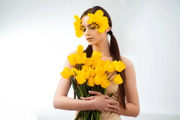 Beauty portrait of a brunette with extended eyelashes in the image of a tulip.    .