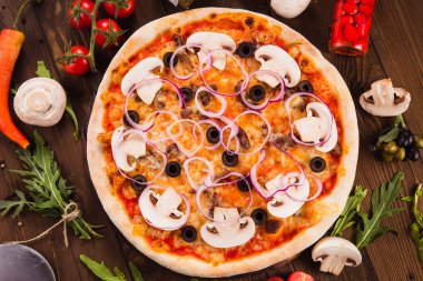 Mantar, zeytin ve ahşap masa üzerinde malzemelerile soğan halkaları ile İtalyan pizza (üst görünümü yakın)