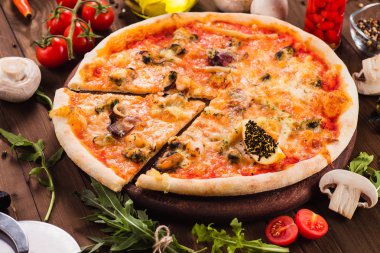 koyu ahşap bir masa (üst görünümü) üzerinde malzemelerle lezzetli İtalyan deniz ürünleri pizza. Tek parça kes