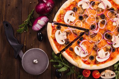 Malzemelerin üzerine ahşap masa (en iyi Görünümü Kapat) ile İtalyan pizza mantar, zeytin ve soğan halkaları. Bir parça kesme