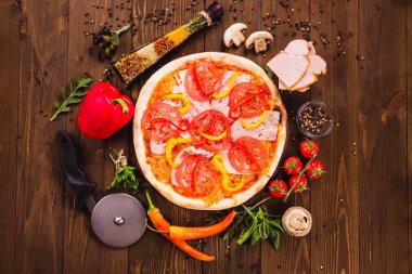 Jambon, domates ve kırmızı biber ile Venedik pizza etrafında malzemelerle koyu ahşap bir arka plan üzerinde (yakın üst görünümü)