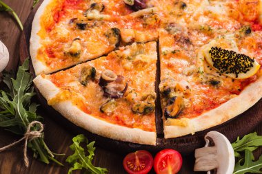 lezzetli İtalyan deniz ürünleri pizza malzemelerin üzerine koyu ahşap bir masa (close). Bir parça kesme