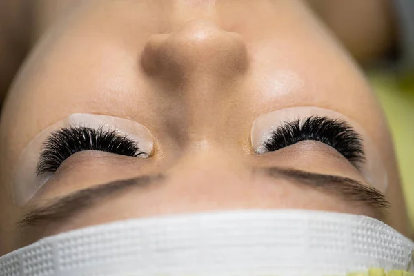 De meester bouwt grote gekleurde wimpers op aan de cliënt. Prep — Stockfoto