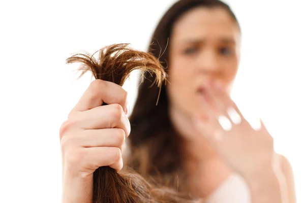 A young woman is shocked by split problem hair. White background — Stock Photo, Image