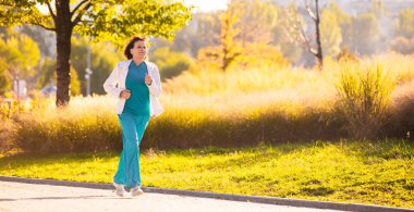 Yaşlı bir kadın gün batımında spor için gidiyor. 