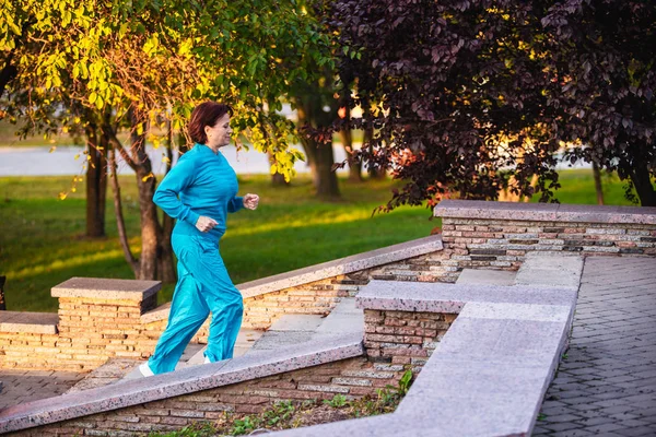 An elderly woman goes in for sports at sunset.