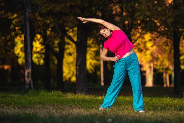 Yaşlı bir kadın gün batımında spor için gidiyor. 