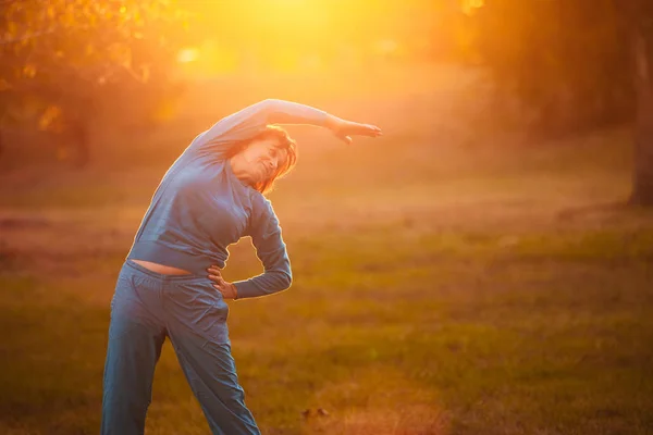 Uma idosa entra para praticar esportes ao pôr do sol . — Fotografia de Stock