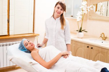 Müşteri bir kozmetolojistle bir resepsiyonda kanepede yatıyor.