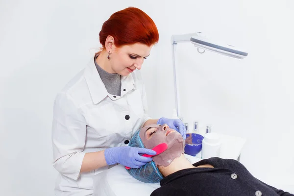 Косметолог надевает на лицо клиента маску в б — стоковое фото