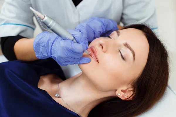 Mujer joven que tiene maquillaje permanente en los labios en el salón de belleza . —  Fotos de Stock