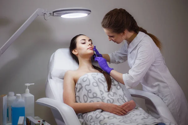 医師の美容師は患者の顔を注射する — ストック写真