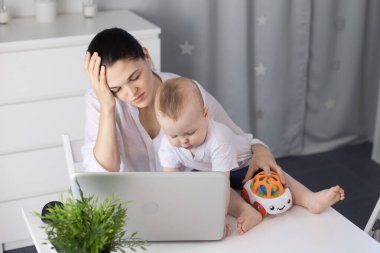 Uykulu bir anne kollarında kaprisli bir çocukla çalışmaya çalışır. Bir kadın baş ağrısı çeker.