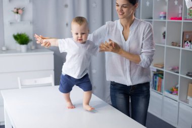 Genç anne küçük oğluna yürümeyi öğretiyor.