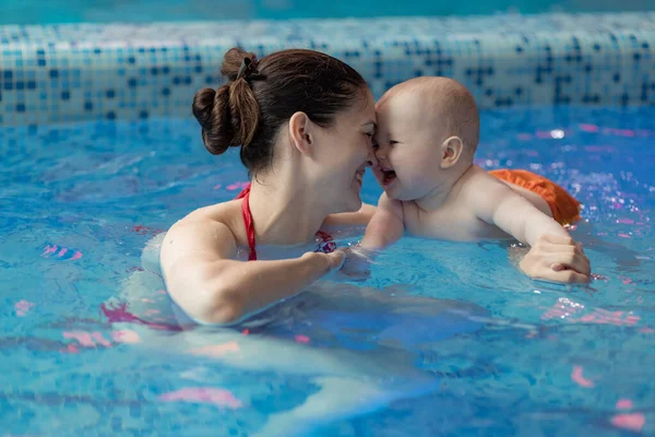 Mom develops baby\'s muscles. Doing various exercises in the pool. Teaches to swim