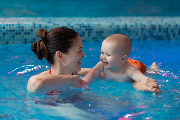 Mom develops baby\'s muscles. Doing various exercises in the pool. Teaches to swim
