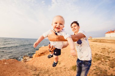 Baba ve oğul. Aile deniz kıyısındaki taşlı plajda geziniyor..