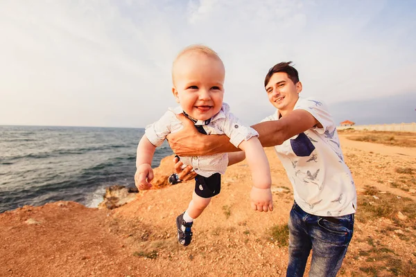 Baba ve oğul. Aile deniz kıyısındaki taşlı plajda geziniyor..