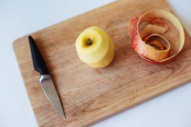 Elma bıçağı ve mutfak masasındaki ahşap bir tahtanın soyulması.