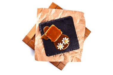 Beyaz arkaplanda izole edilmiş siyah bir kaide üzerinde karamel ve fındıklı tatlı.