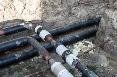 Isıtma sistemi için ardışık düzen yapmak için kum çevresinde ele geçen boru hattı inşaat alanında. Bölge Isıtma sistemi yeniden inşası.