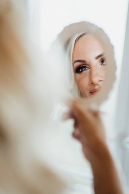 Bride, young pretty woman looks in the mirror. Getting ready pictures of a wedding clipart