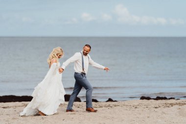 Kumsalda koşan mutlu yeni evli çift. Kumsalda düğün