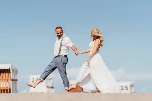 Ευτυχισμένο νιόπαντρο ζευγάρι που περπατάει στην παραλία. Γάμος στην παραλία — Φωτογραφία Αρχείου