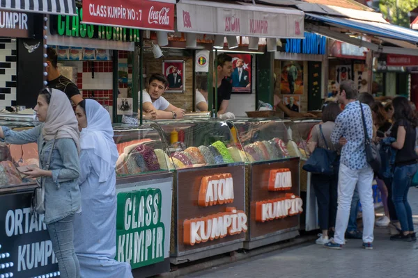 Istanbul, Türkiye - Temmuz 2018: Birçok kiosklar geleneksel Türk fastfood, canlı alanında ünlü Ortaköy İskelesi alanı gün zaman sunuyoruz. Satıcılar deneyin veya tatlı waffle yemek için yoldan geçenler tout ve patates destekli