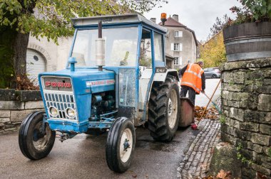 Chateau-Chalon, Fransa-11 Kasım 2014: Çöpçü eski bir Ford Traktör yoIda temizler.