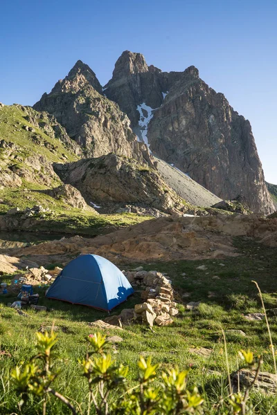 The Pic du Midi d\'Ossau (2884 m) with summer sky and a blue tent in the foreground. It is a mountain rising above the Ossau Valley in the French Pyrenees