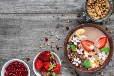 kakao veya çikolata ve muz protein güler yüzlü çiçek ve nar taneleri rustik masada granola ile çilek, Bovling. üstten görünüm. sağlıklı kahvaltı