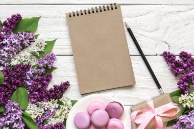 Yaratıcı düzen eflatun çiçekler, Bademli kurabiye, hediye kutusu ve beyaz ahşap zemin üzerinde boş hipster defter ile yaptı. Düz yatıyordu. üstten görünüm. Düğün çerçeve. bahar en az kavramı
