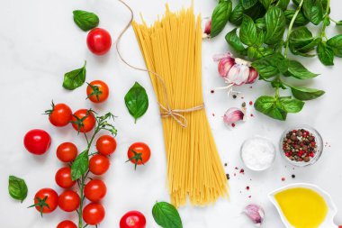 pişmemiş makarna spagetti domates, sarımsak ve beyaz mermer zemin üzerine fesleğen. pişirme kavramı. üstten görünüm. düz lay