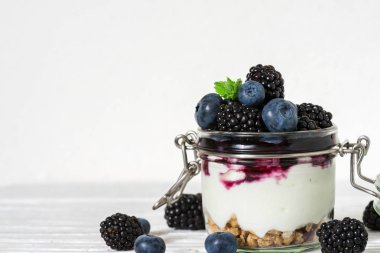 sağlıklı yoğurtlu taze yaban mersini, böğürtlen, granola ve nane Beyaz ahşap masa üzerinde bir kavanoza. sağlıklı kahvaltı. kopya alanı ile yakın çekim