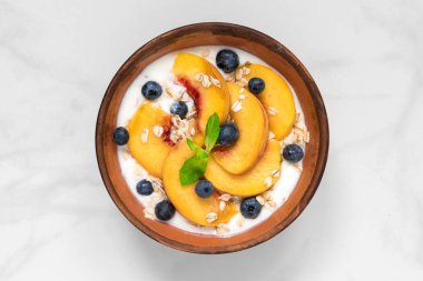 Şeftali, yulaf, nane ve sağlıklı kahvaltı için yaban mersini ile Yunan yoğurt kase. üstten görünüm