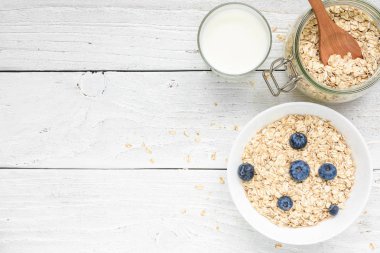 Taze yaban mersini ve beyaz ahşap bir masa üzerinde süt ile yulaf gevreği. sağlıklı kahvaltı. kopya alanı ile üstten görünüm