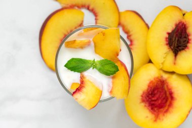 sağlıklı meyve yoğurtlu Taze şeftali ve nane beyaz mermer masada bir bardak. sağlıklı kahvaltı. üstten görünüm