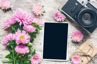 boş fotoğraf çerçevesi ve vintage retro fotoğraf makinesi ile güzel buket pembe aster çiçek ve hediye kutusu. tatil ya da düğün arka plan. kadar alay et. üstten görünüm. Vintage tonlama