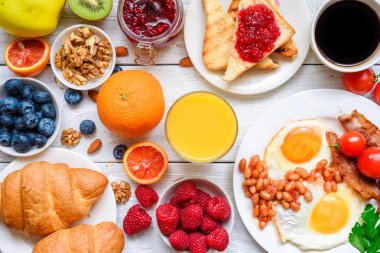 Kahve, kızarmış yumurta, pastırma, fasulye, kruvasan, fındık, meyve ve çilek ile portakal suyu da dahil olmak üzere Servis Kahvaltı. üstten görünüm