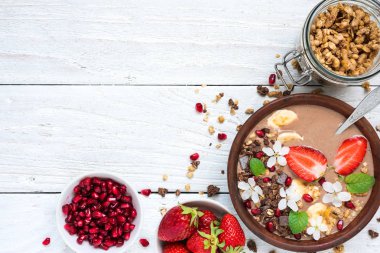 kase çikolata granola, muz, çilek ve nane ve çiçekler ile sağlıklı kahvaltı için bir kaşık ile tepesinde nar ile kakao güler yüzlü. kopya alanı ile üstten görünüm