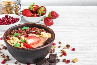 Beyaz ahşap masa granola, çilek ve nar tohumları ile çikolatalı muz protein güler yüzlü kase. kopya alanı ile kapatın. sağlıklı kahvaltı